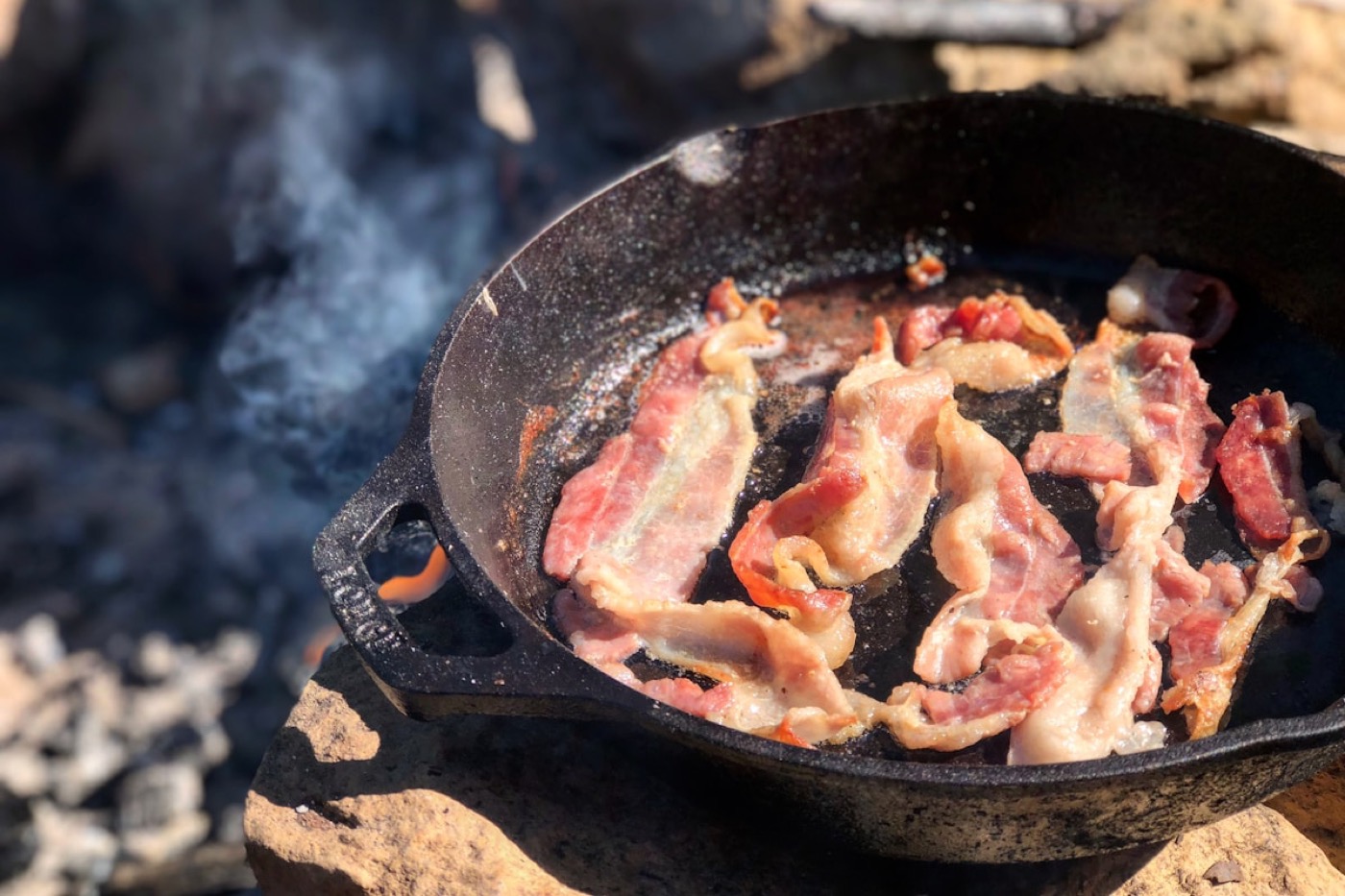Bacon sizzling in a cast-iron skillet