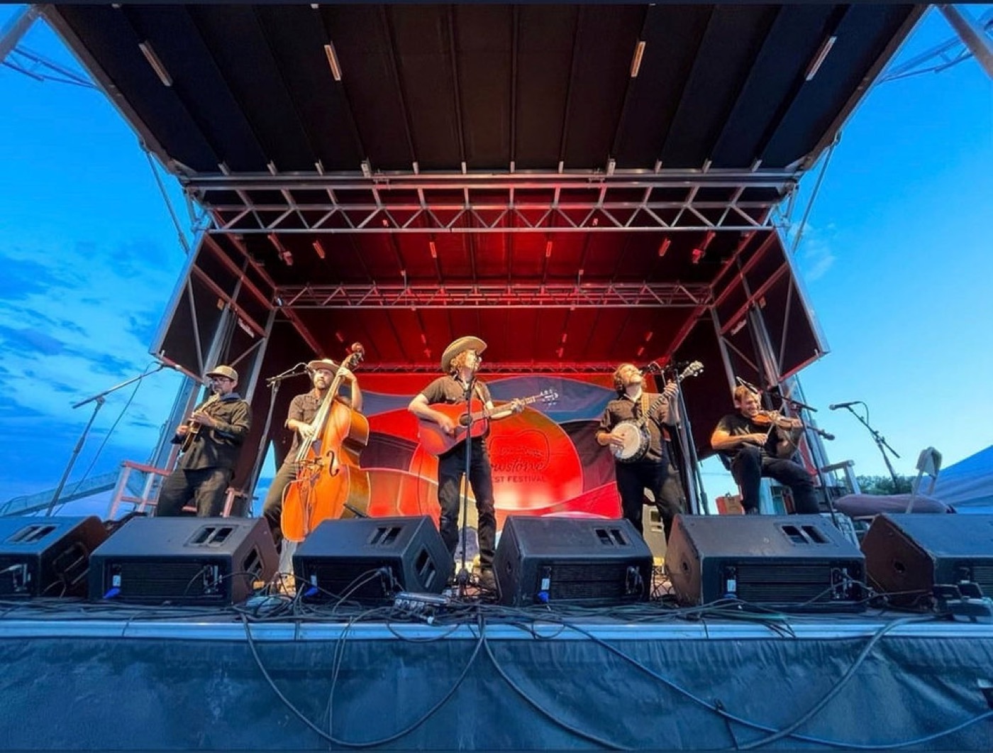 A bluegrass band performing on an outdoor festival stage