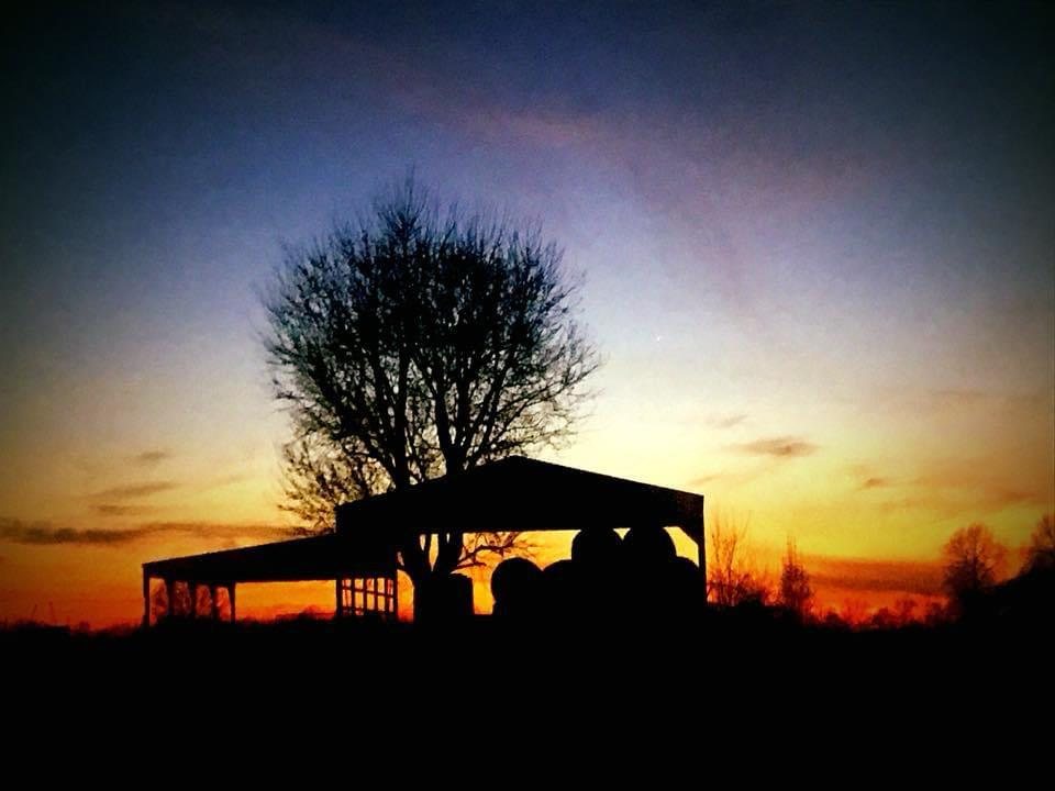 Farm structure beneath a darkening sunset